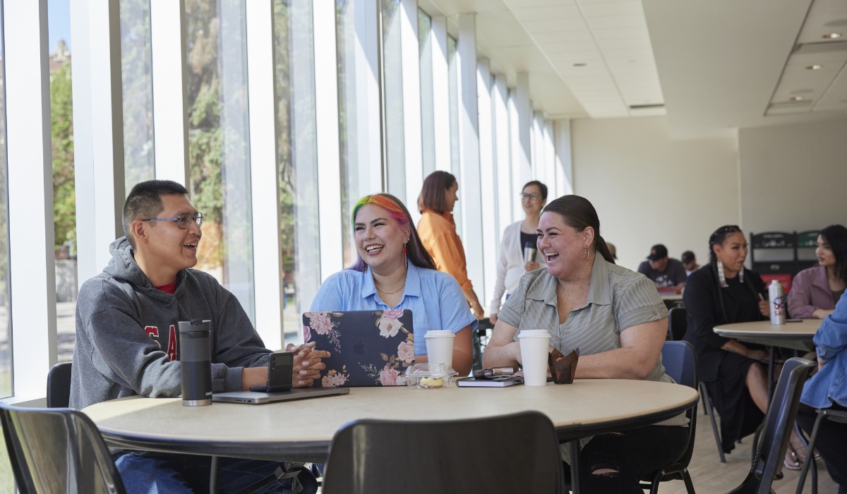 A group of students engaged in conversation at a coffee shop, showcasing a sense of community and collaboration.