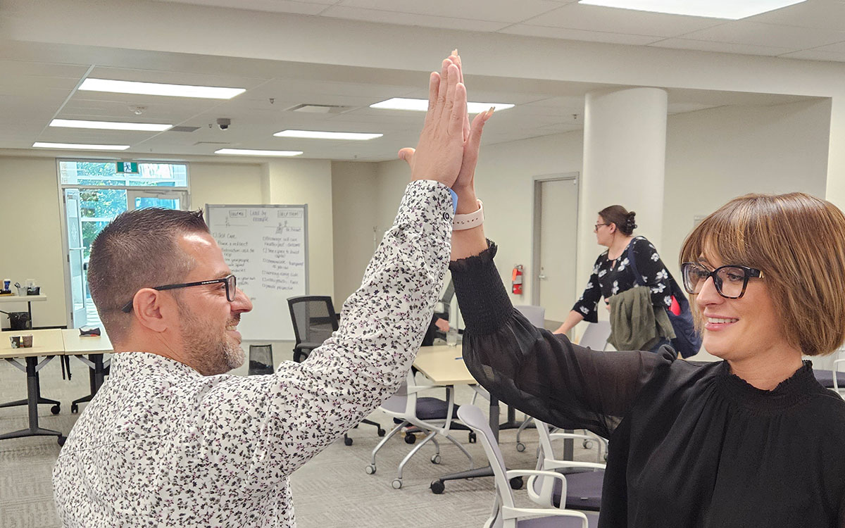 Two members of the connectFirst team give each other a high five in one of SAIT's classrooms.