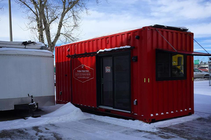 An outside shot of a red shipping container in a hut.