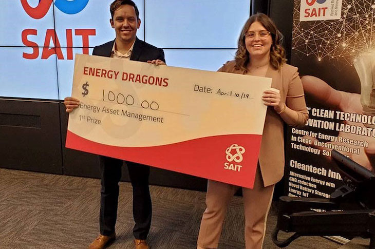 Two people hold onto a large cheque