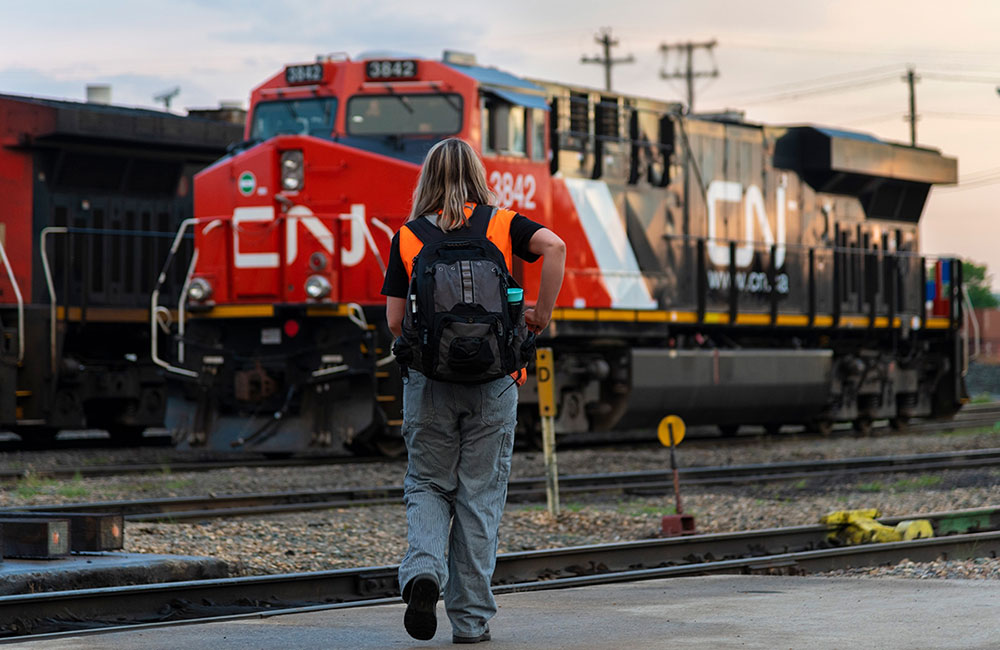 railroader Leslie Lukan walking toward a stopped train wearing high-vis vest