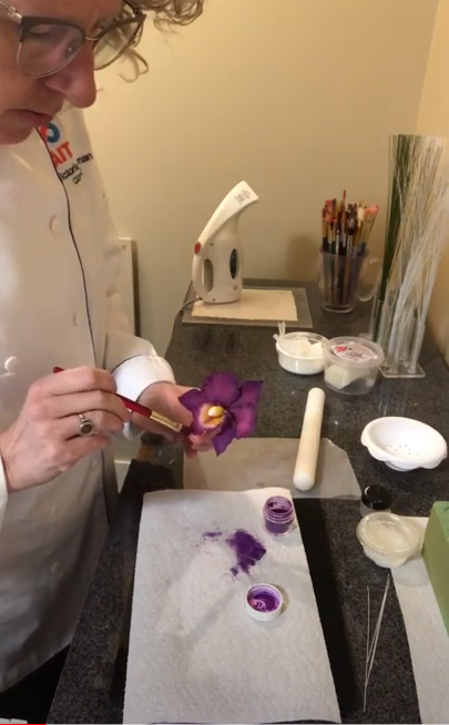 Baking and Pastry Arts Instructor Victoria German demonstrates the final step in creating a decorative catteyla orchid.