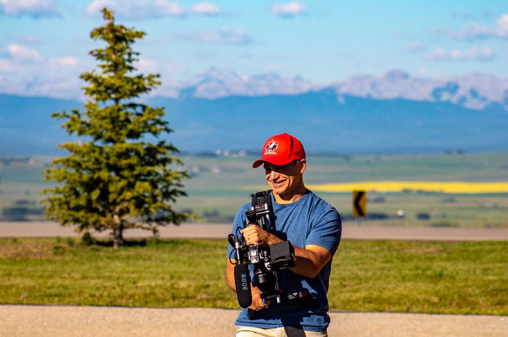 Grant Nolin onsite for a video shoot in the countryside with mountains in background
