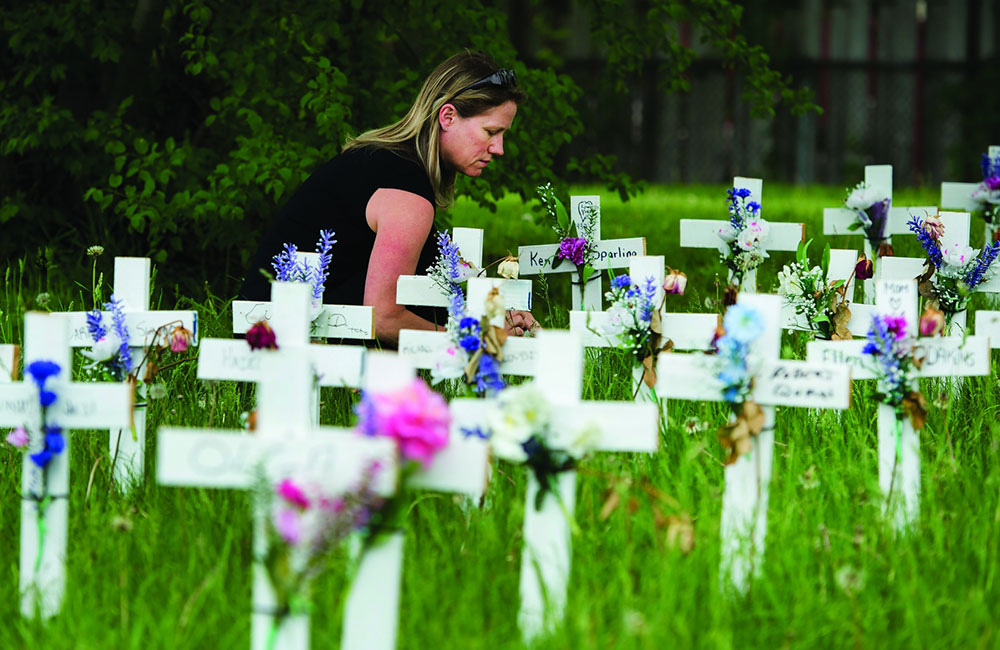 A woman visits her father's cross along with others displayed outside the Camilla Care Community centre marking the deaths of multiple people that occurred during the COVID-19 pandemic in Mississauga, Ont., on Friday, May 29, 2020.