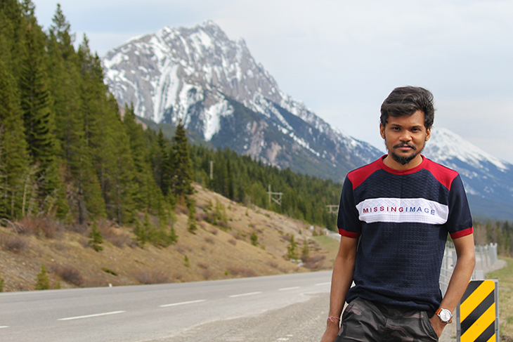 man in tshirt standing with mountain background