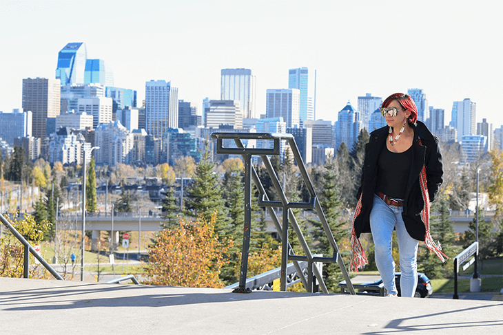 Women walking up a set of stairs with downtown Calgary behind her.