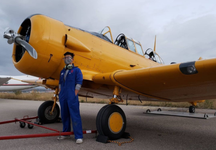 man in blue jumpsuit standing beside yellow aircraft