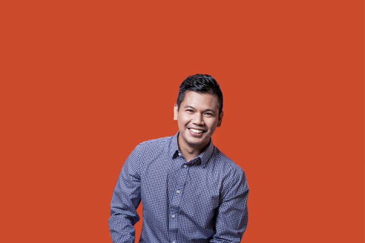 man smiling with orange backdrop