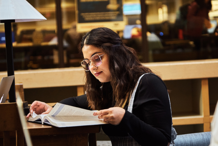 girl in glasses studying from textbook
