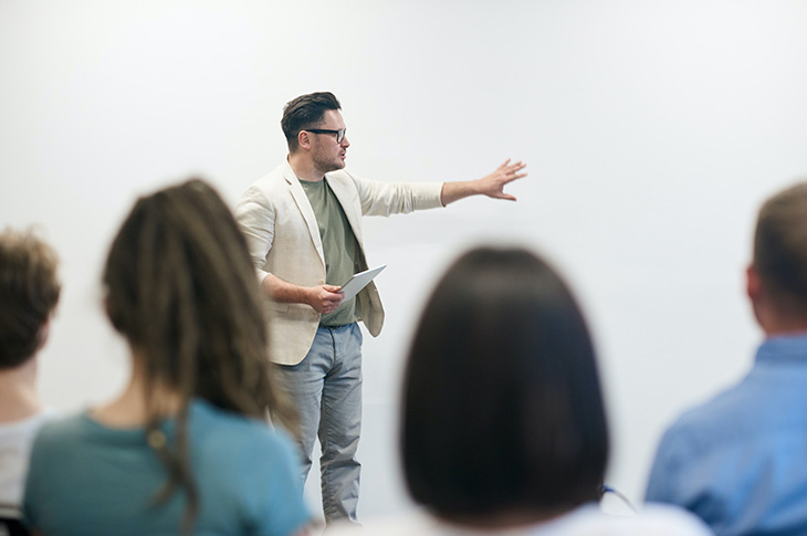 man standing in front of white board speaking to audience