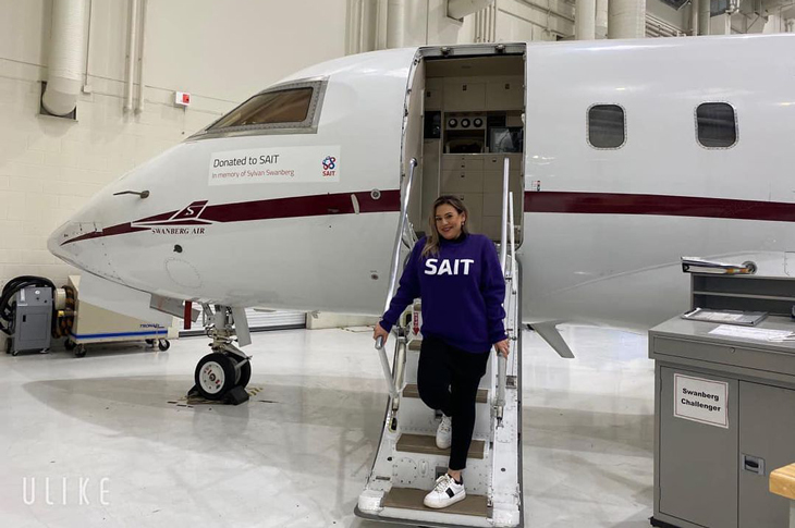 SAIT student standing in front of aircraft