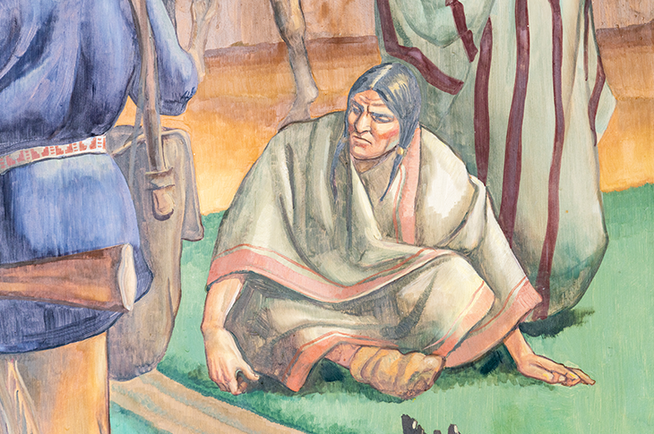 Close up of Indigenous person sitting cross legged on mural