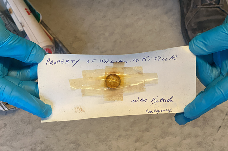 A major clue within the package, a note — "Property of William M. Kitiuk" — and a 1967 centennial dime.