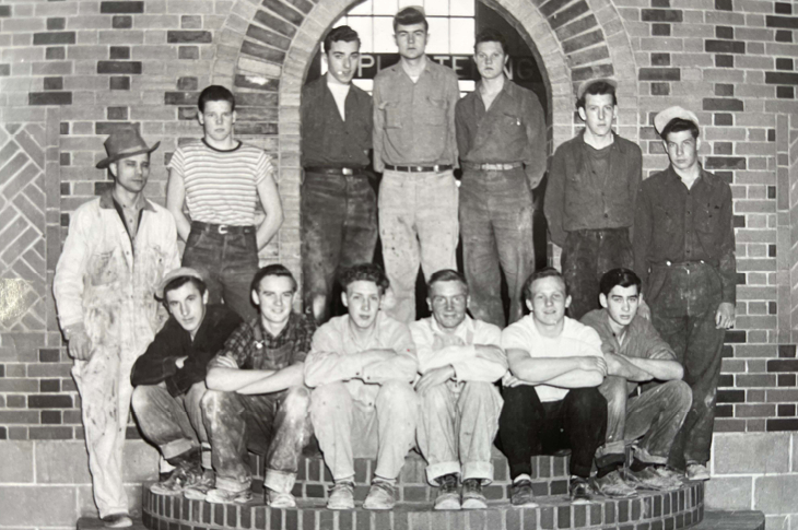 Donald Kitiuk pictured far left in white overalls posing with his students in the bricklaying program.