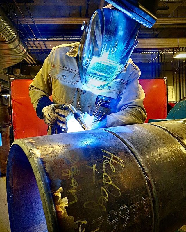 A person welding a metal pipe