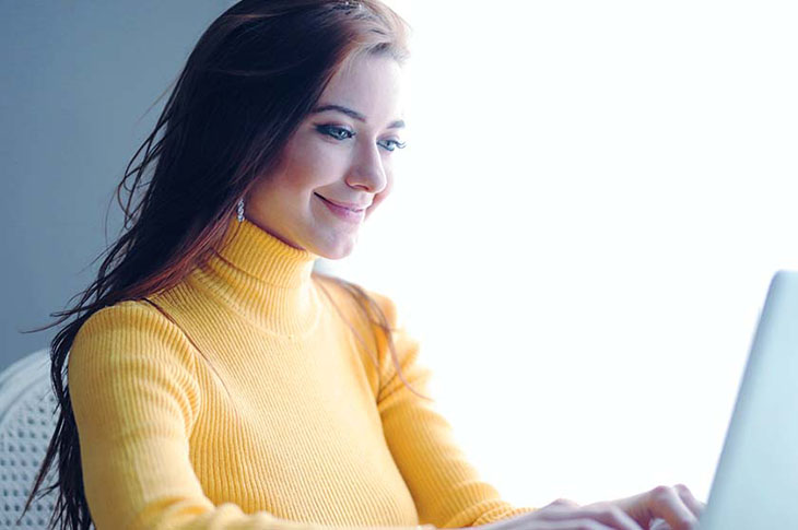girl in yellow sweater on laptop