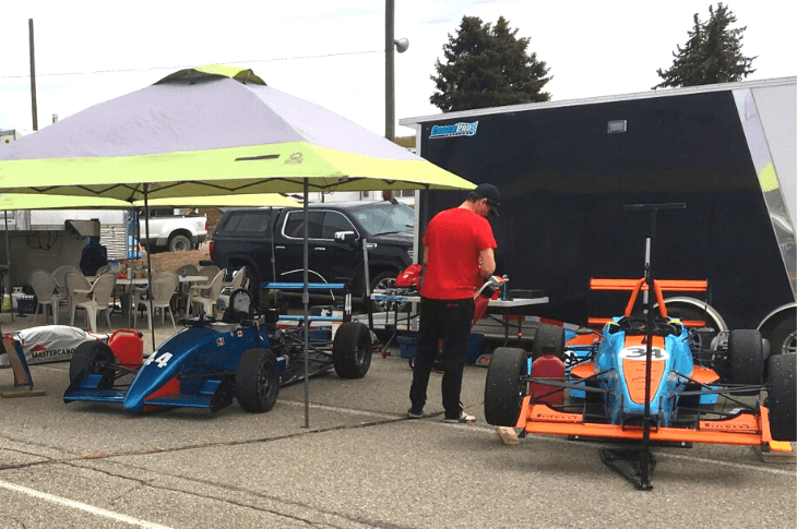 two formula race cars in pit area