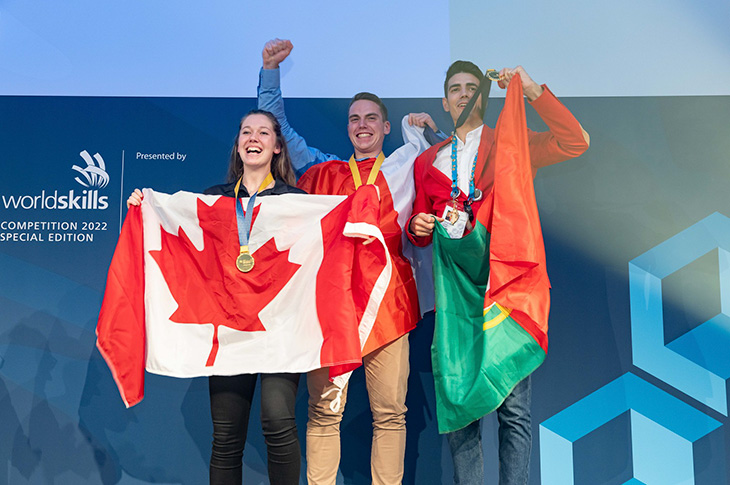 SAIT alumna Korae Nottveit celebrates her WorldSkills gold medal on the podium while holding a Canadian flag