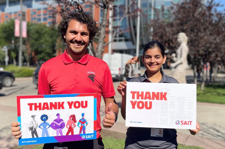 photo of two students posing with thank you signs