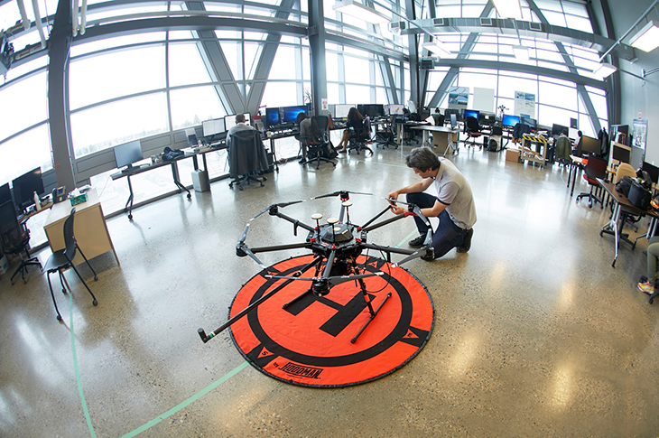 Person crouched next to a drone at SAIT