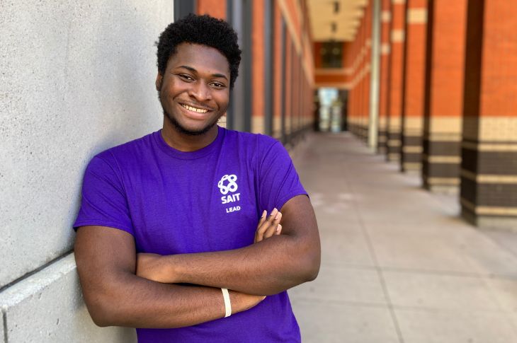 Young black male wearing a purple shirt smiling