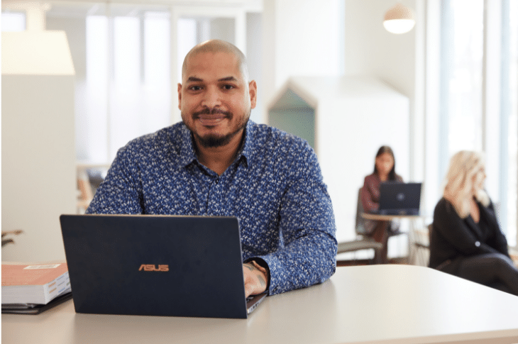 photo of professional grad sitting with laptop in an open office space