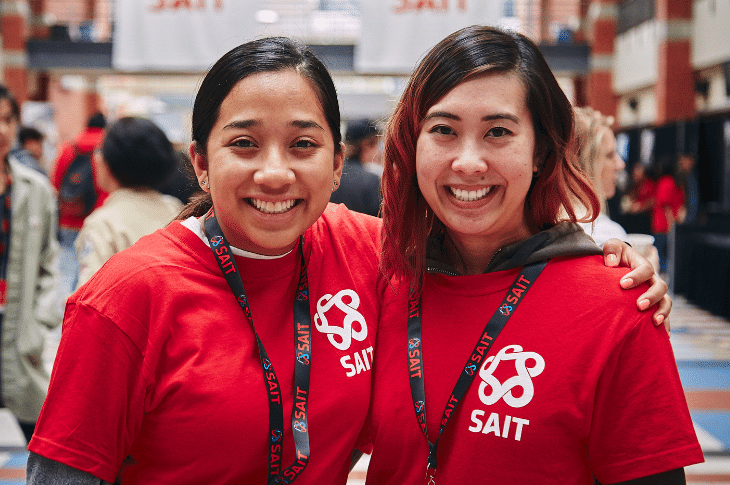 Two female volunteers wearing red tshirts smiling