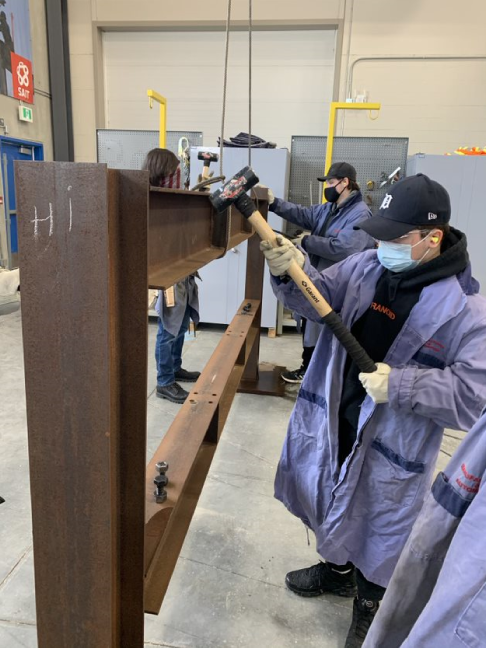 Students using hammers on steel beam