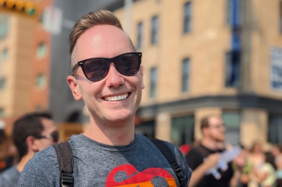 Lukas Valentine smiles in downtown Calgary while wearing a SAIT pride t-shirt