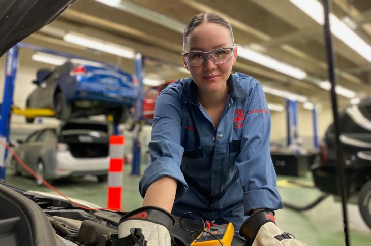 Female automotive student working on car