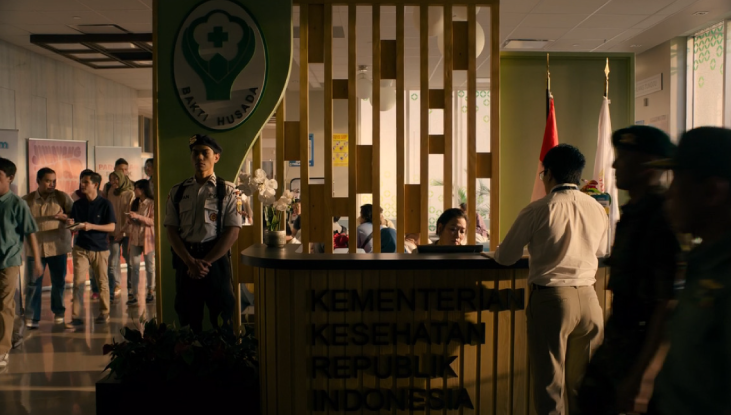 People walk the halls of a busy Jakarta hospital. A hospital desk with a receptionist behind it is in the centre of the shot featured in The Last of Us.