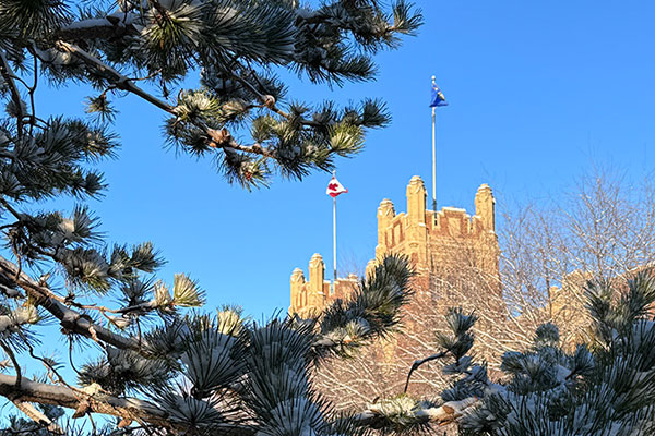 The top of the Heritage Hall building, seen through evergreen trees.