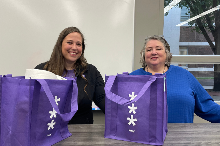 two women with purple tote bags
