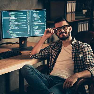 Smiling man sitting at a computer using a software development course to help create a new development code