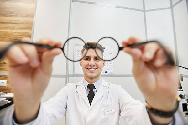 A doctor holds up glasses to the camera