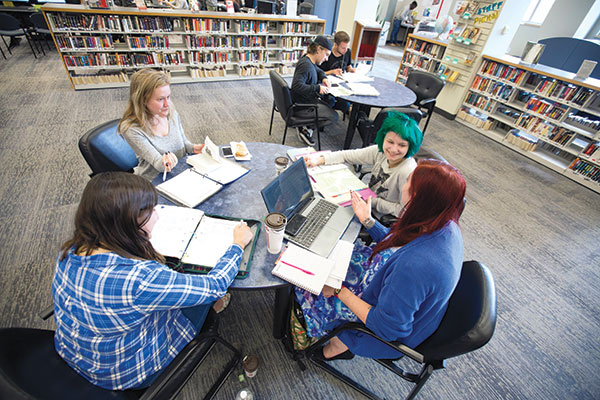 Four students sit around a table at the Reg Erhardt Library at SAIT.