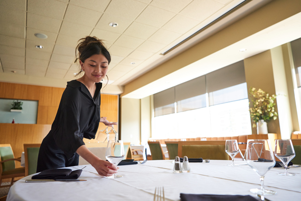 A Hospitality and Tourism Management students sets a table at the Highwood Restaurant and Bar.