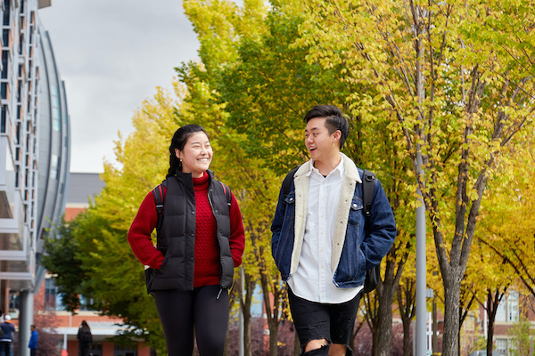 Two students walk around in the fall