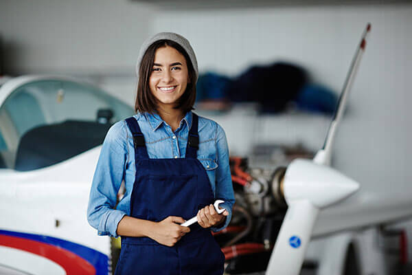Women holding wrench and overalls, smiling