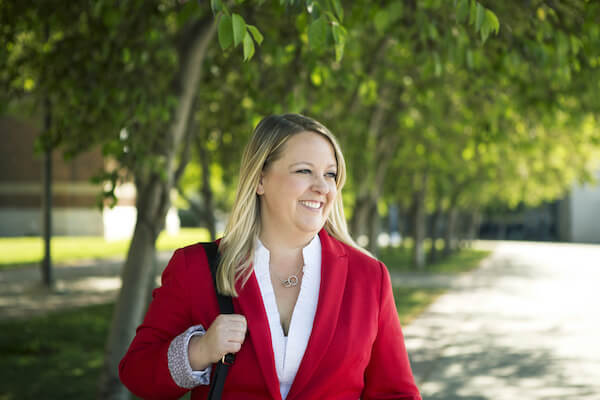 A women stands outside in the summer wearing a red blazer. 