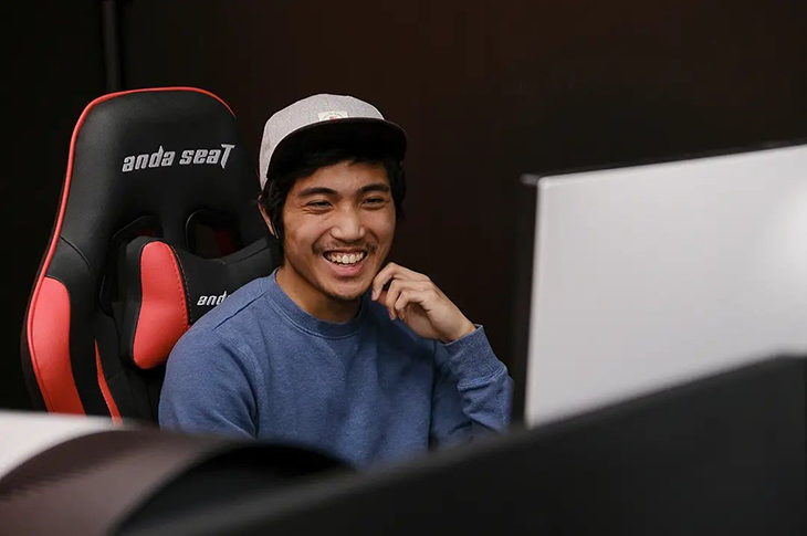 A student smiles at the camera sitting in a gaming chair