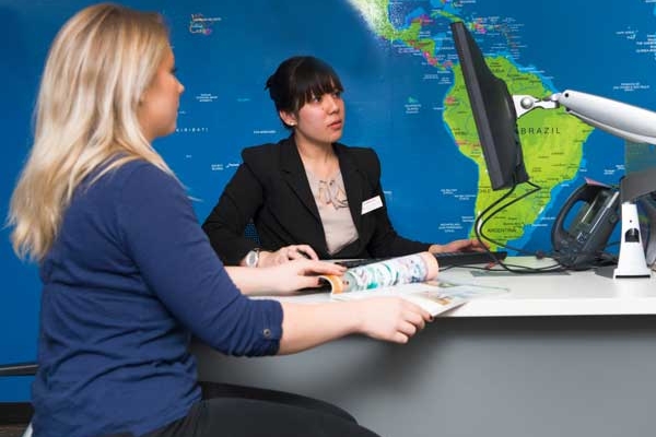 A Travel and Tourism student works with a client to plan a trip while in Destinations, SAIT's student-run travel centre