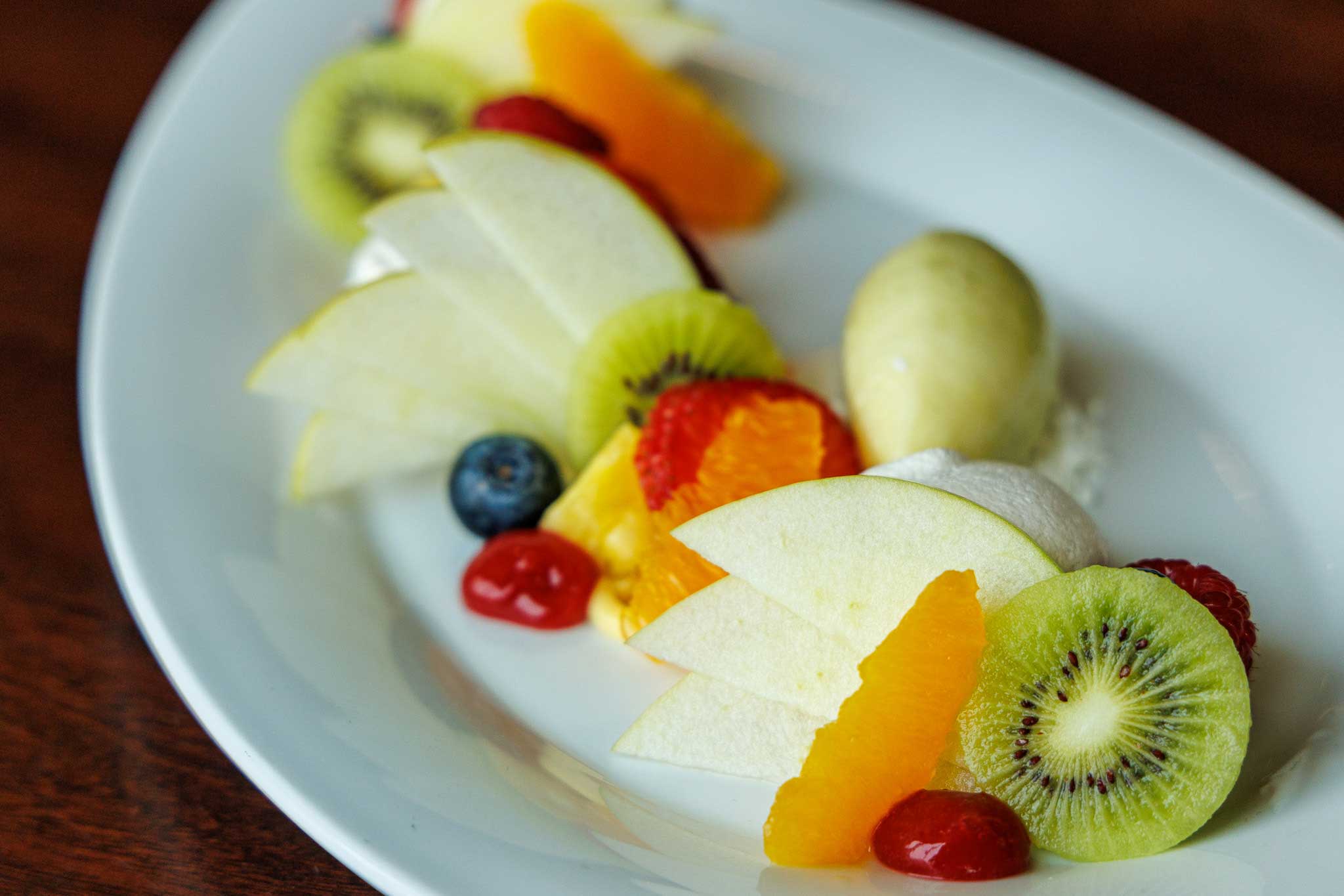Various fresh fruits with meringue and sorbet presented on white plate