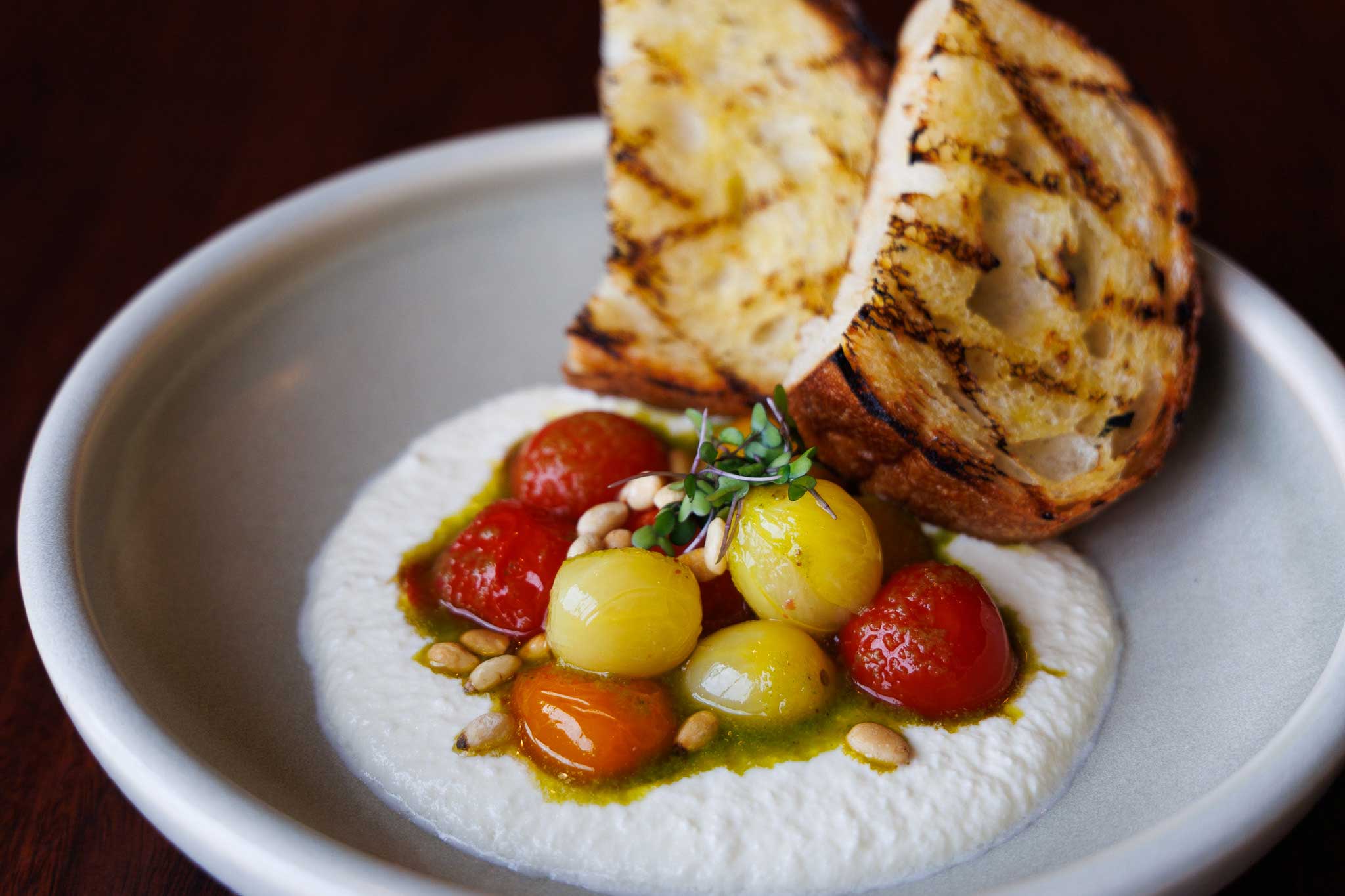 Whipped feta dip with cherry tomatoes and pine nuts served with grilled sourdough bread