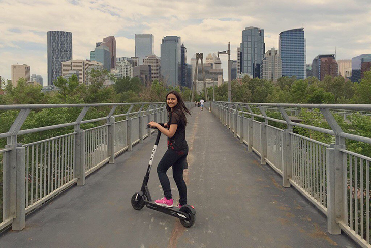 Woman on scooter going over bridge