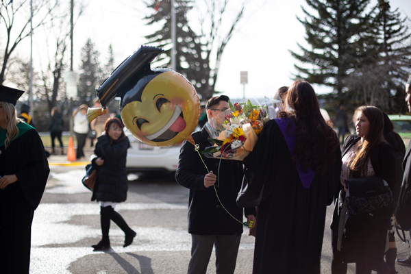 People standing outside with a graduation balloon