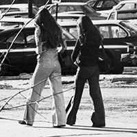 Two women walking in a parking lot.