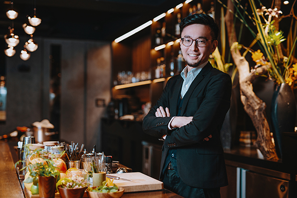 Well dressed man standing behind a bar and smiling
