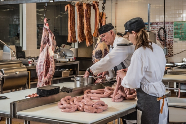Student and instructor preparing sausages in SAIT butchery kitchen