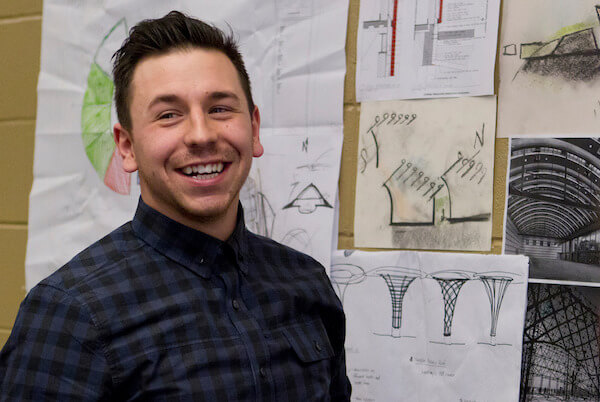 Man looks past camera with drawings behind him
